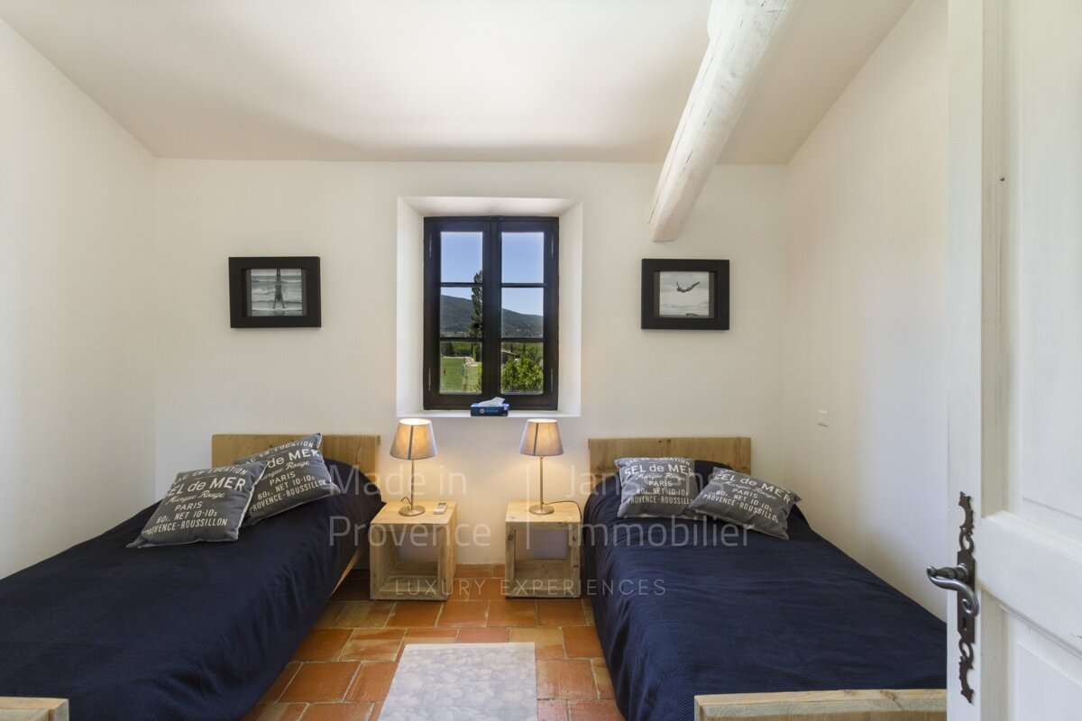 A bedroom with two beds and a clock that says made in provence