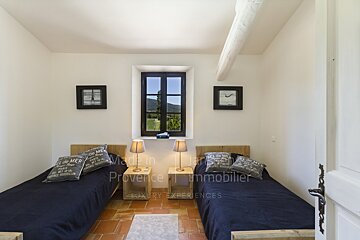 A bedroom with two beds and a clock that says made in provence