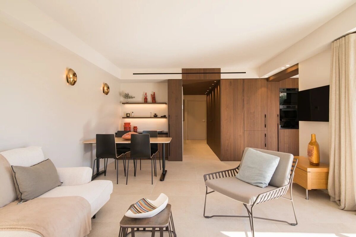 A modern, minimalist living and dining space with warm wood accents, neutral furniture, and clean lines.