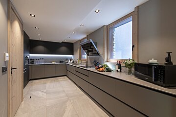 A kitchen with a microwave and a bottle of wine on the counter