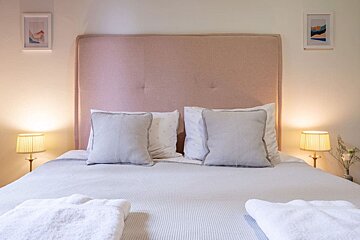 A bed with a pink headboard and grey pillows