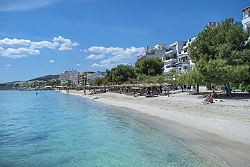 A beach with umbrellas and buildings in the background