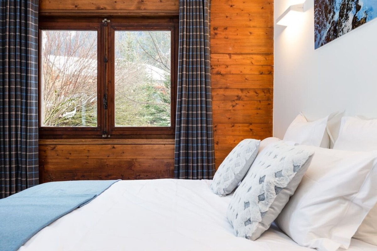 A bedroom with wood paneling and a large window