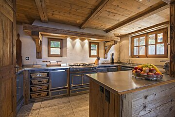 A kitchen with a stainless steel counter top and wooden cabinets