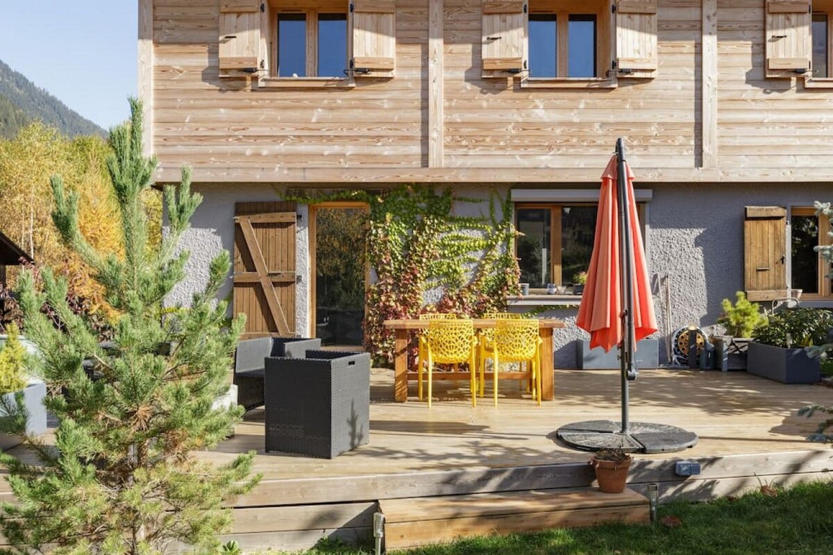A red umbrella sits in front of a wooden house