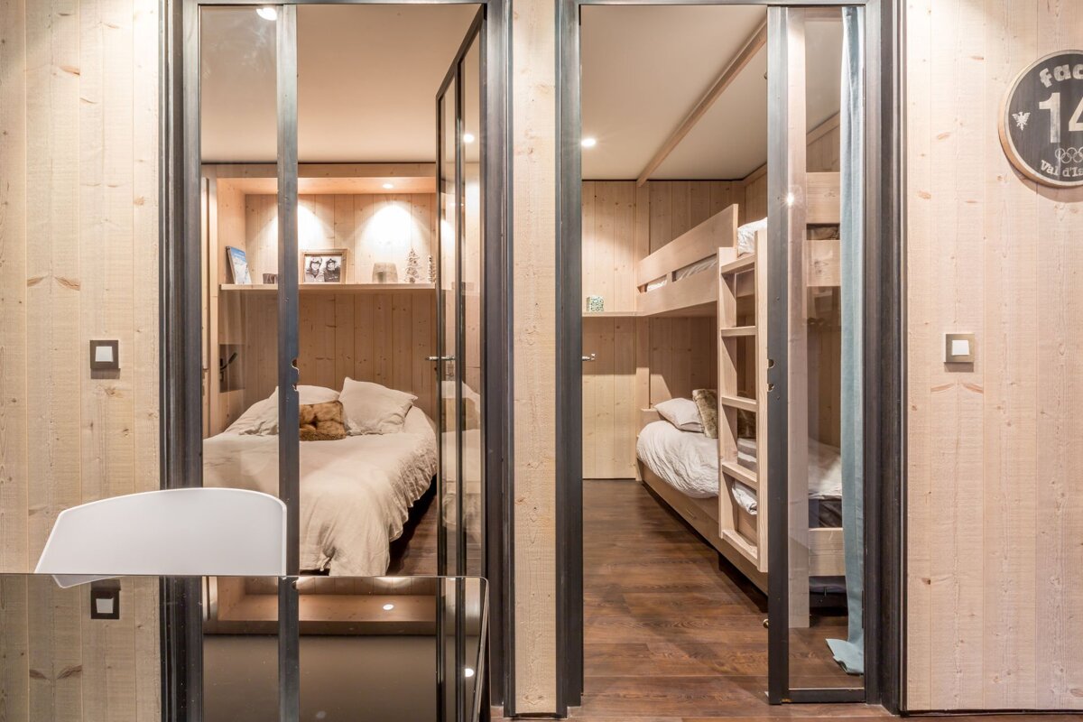 A bunk bed with a red blanket in a wooden room