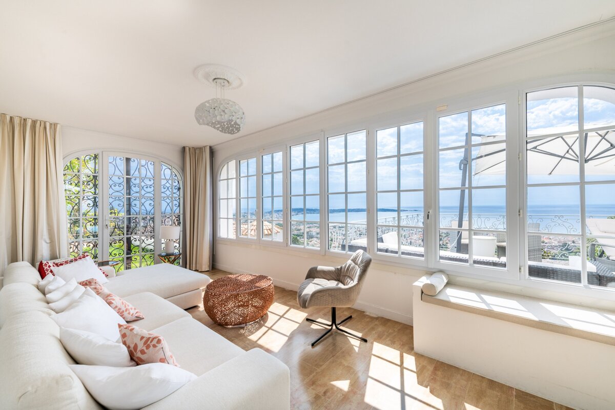A living room with a couch and chair and a view of the ocean