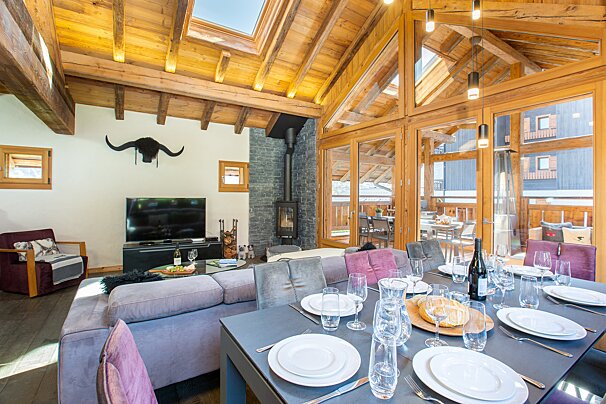 A dining table with plates and glasses and a bottle of wine