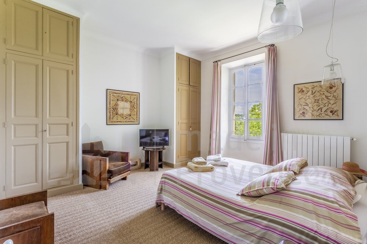 A bedroom with a bed a chair and a television