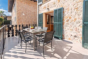 A table and chairs on a balcony with green shutters