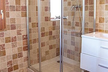 A bathroom with a walk in shower and a sink