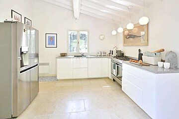 A kitchen with white cabinets and a stainless steel refrigerator
