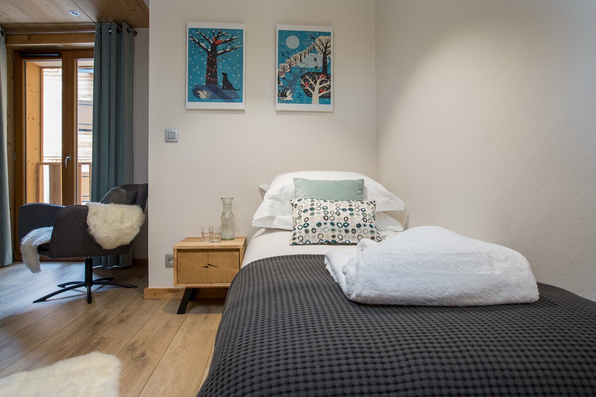 A bedroom with a single bed and two paintings on the wall