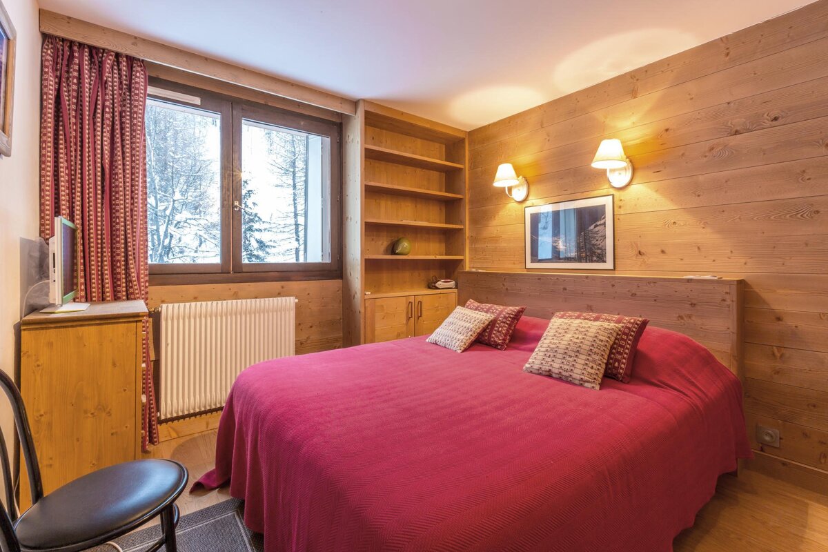 A kitchen with wooden cabinets and a clock that reads 11:57