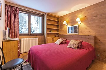 A kitchen with wooden cabinets and a clock that reads 11:57