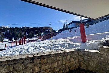 A view of a ski slope from a balcony with a sign that says ski house