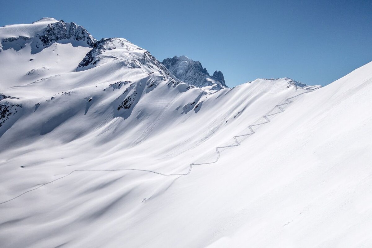 A snowy mountain with a blue sky in the background