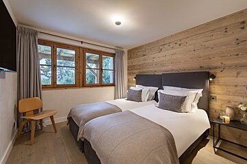 A bedroom with two beds and a chair