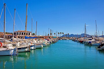 A row of boats are docked in a harbor and one of them says milan on the side