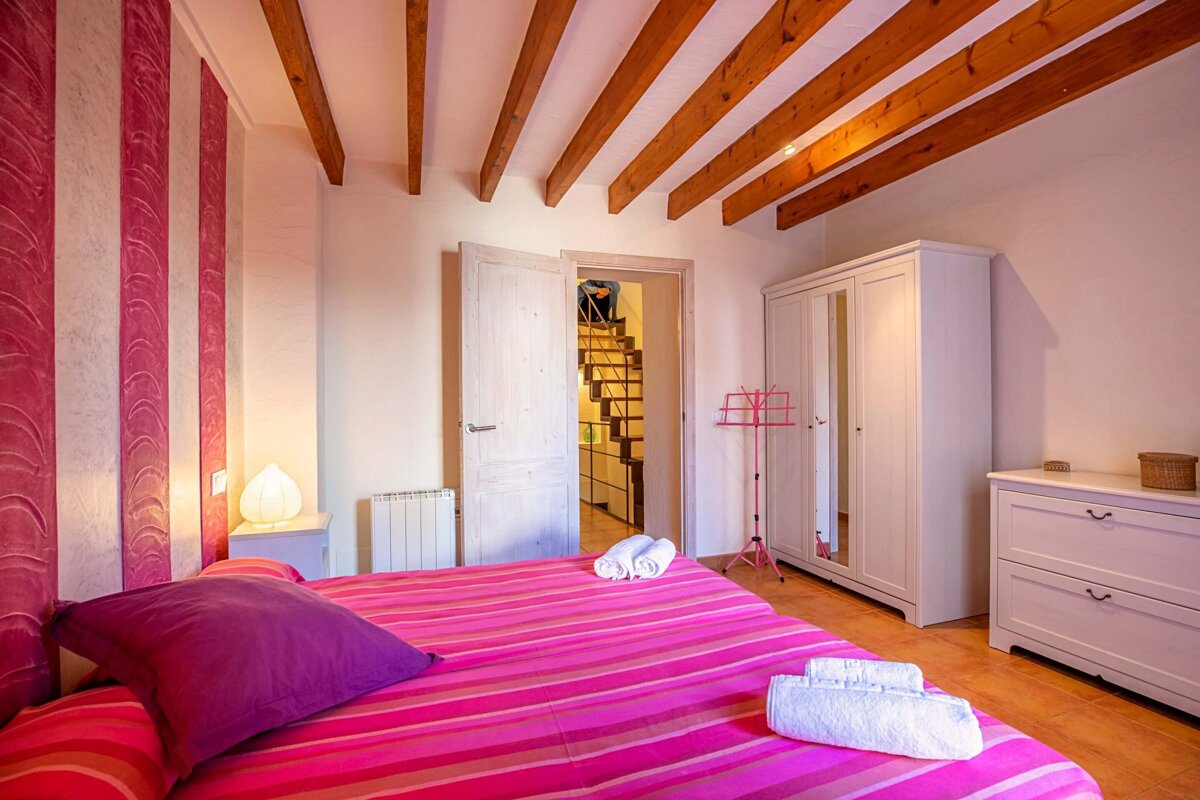 A bedroom with a pink bed and a white dresser