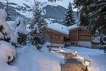 A snowy path leading to a cabin with a mountain in the background