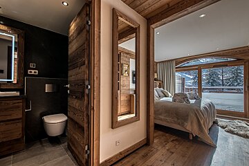 A bathroom with a toilet and a mirror on the wall