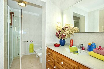 A bathroom with a sink a toilet and a vase of flowers