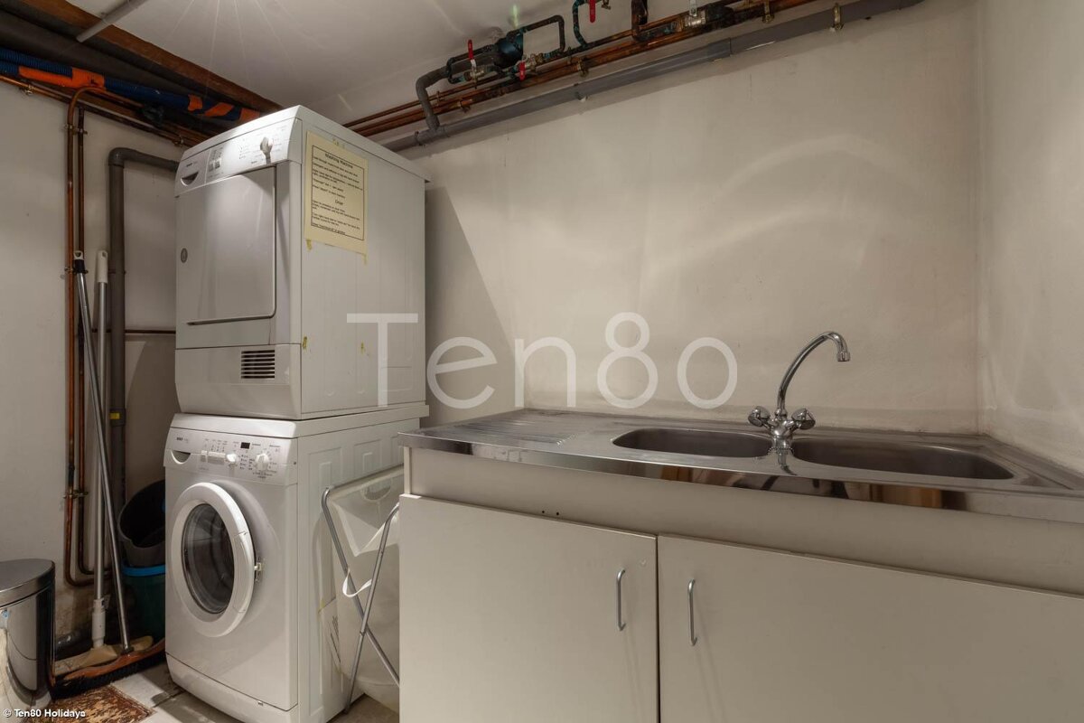 A washer and dryer are stacked on top of each other in a laundry room labeled ten80