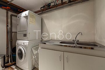 A washer and dryer are stacked on top of each other in a laundry room labeled ten80
