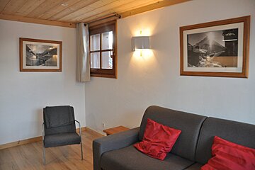 A living room with a couch and two framed pictures on the wall