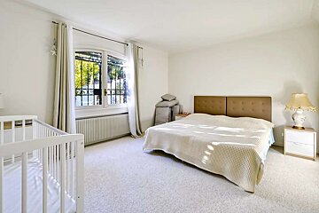 A bedroom with a bed a nightstand and a crib