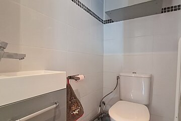 A bathroom with a toilet a sink and a towel hanging on the wall