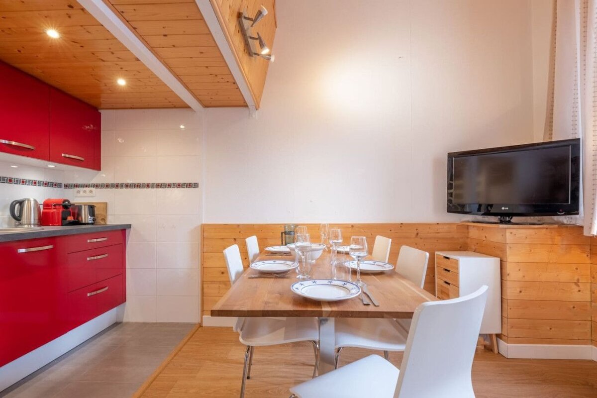 A kitchen with red cabinets and a flat screen tv