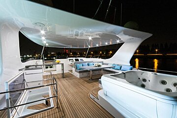 A boat with a jacuzzi on the deck at night