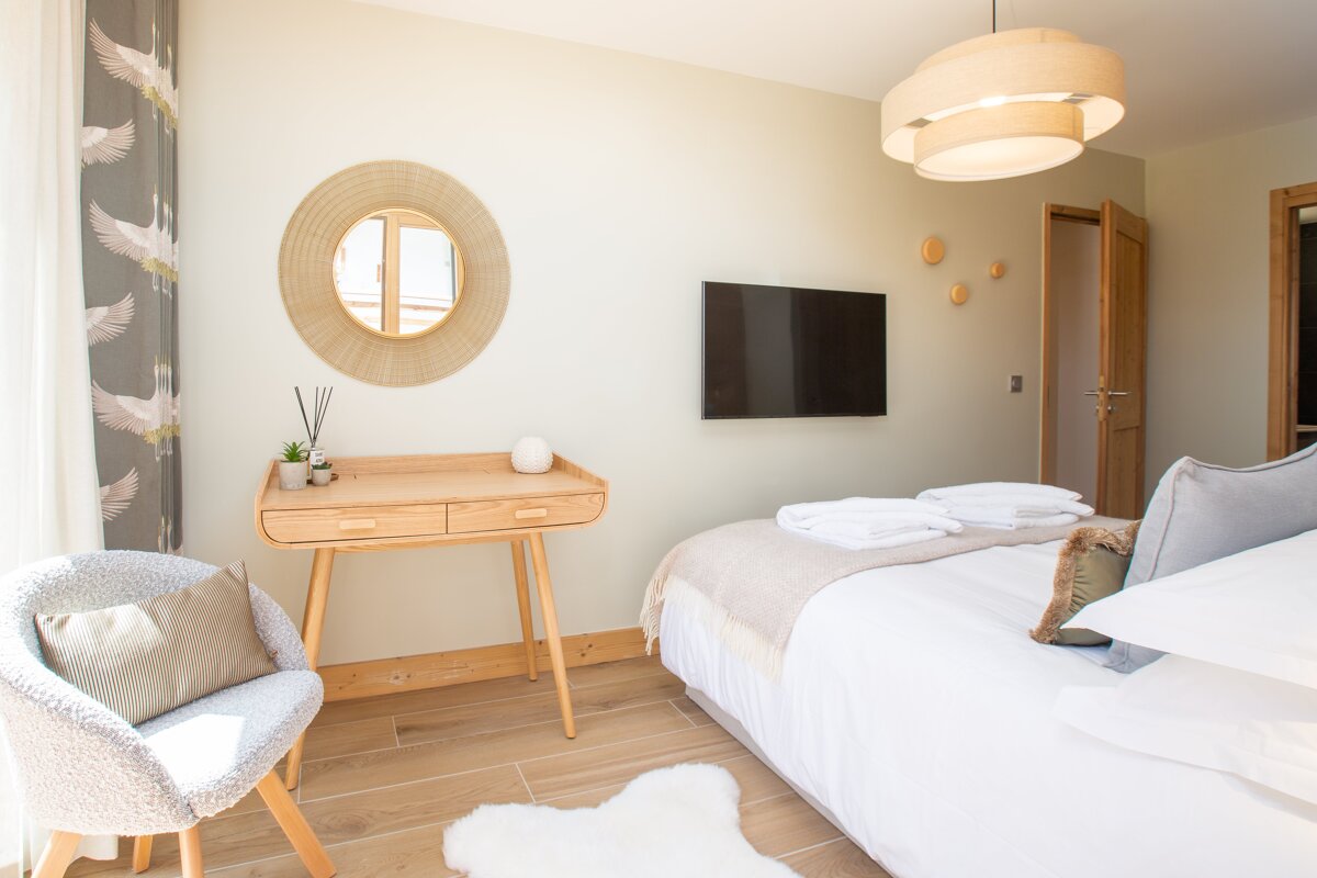 A bedroom with a bed a desk and a flat screen tv