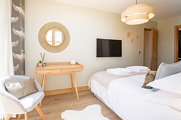 A bedroom with a bed a desk and a flat screen tv