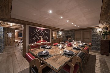 A dining room with a long wooden table and chairs