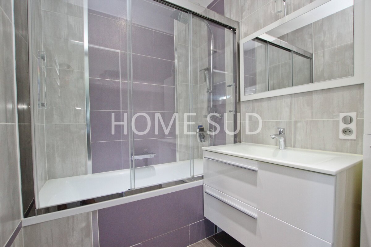 A bathroom with purple tiles and the word home sud on the wall