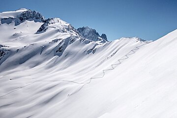 A snowy mountain with a blue sky in the background