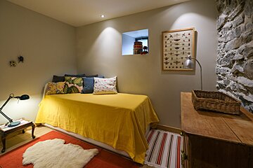 A bed with a yellow blanket and pillows in a room