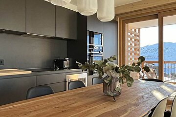 A kitchen with black cabinets and a wooden table with a vase of flowers on it