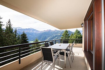 A balcony with a table and chairs overlooking the mountains