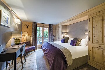 A bedroom with a large bed and a desk