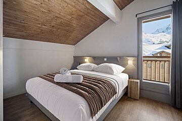 A bedroom with a bed and a window with mountains in the background