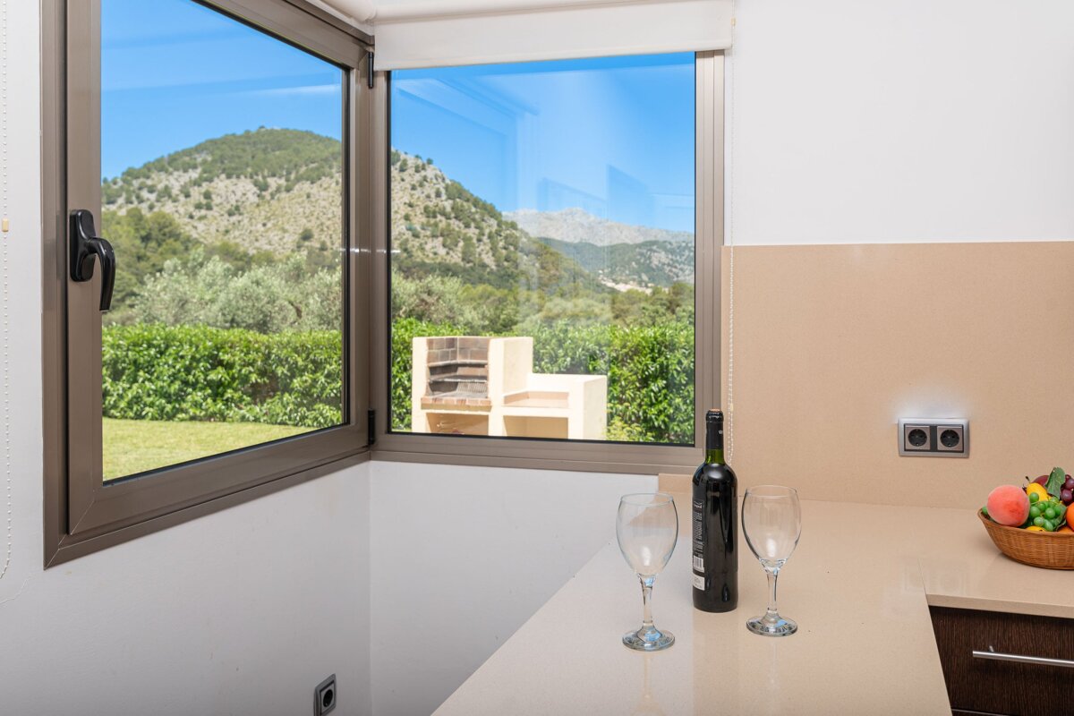 A bottle of wine sits on a counter next to two glasses