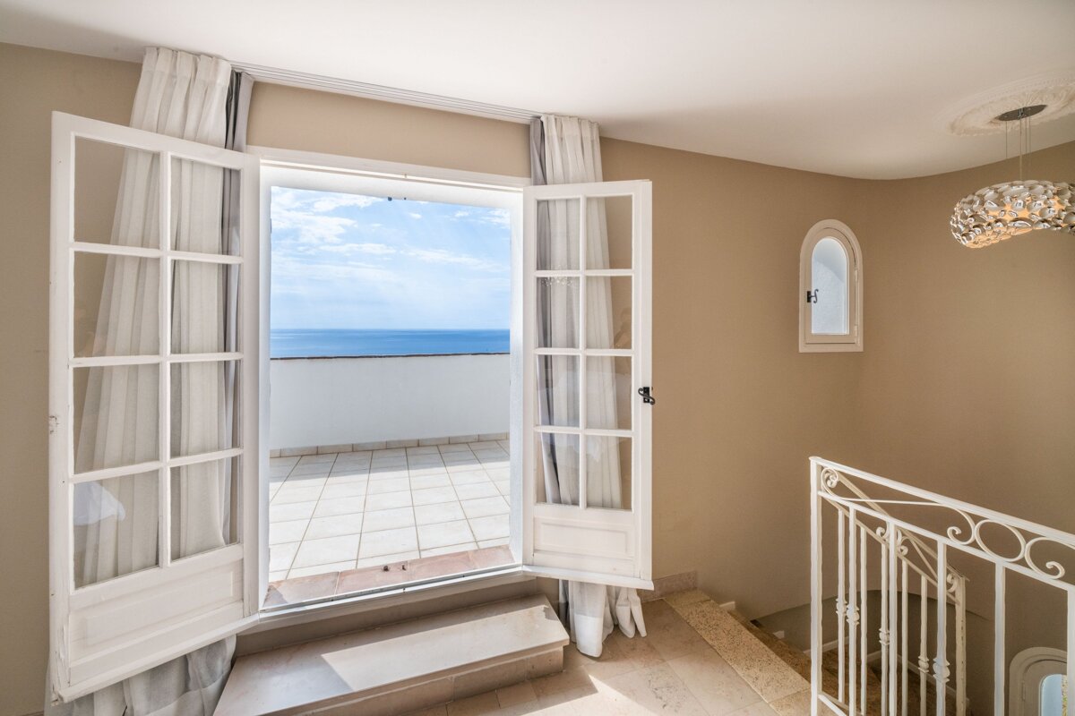 A balcony with a view of the ocean and stairs leading up to it
