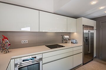 A kitchen with white cabinets and a stainless steel refrigerator
