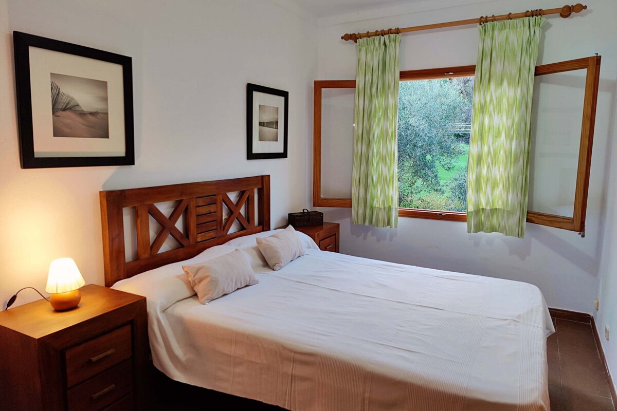 A bedroom with a bed and a window with green curtains