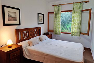 A bedroom with a bed and a window with green curtains