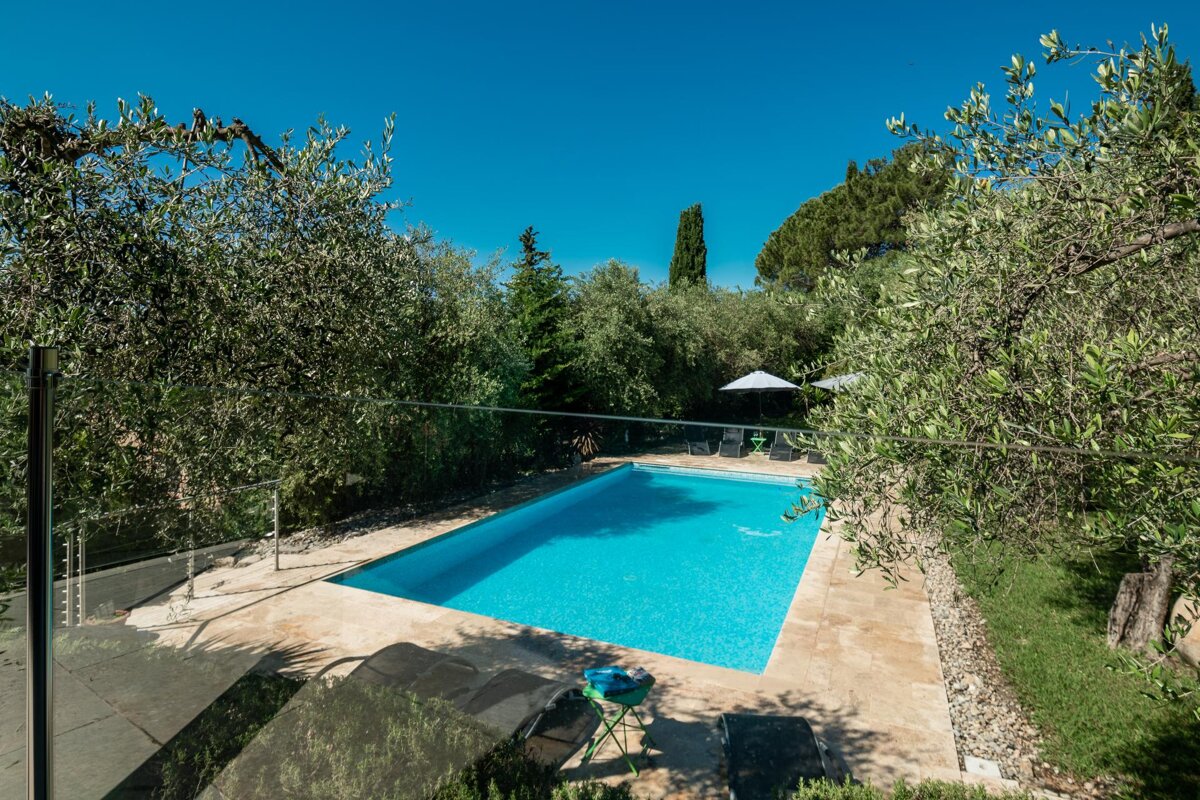 A large swimming pool surrounded by trees and chairs